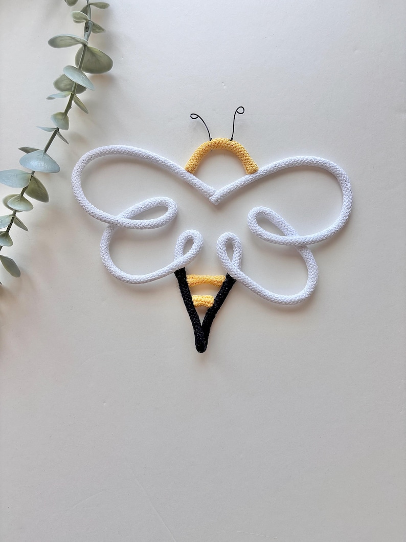 Cute core bee decor styled on wall hooks in light nursery space