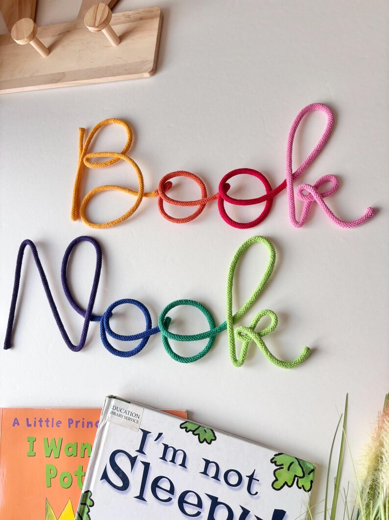 Rainbow Book Nook wall sign above kids reading corner with books