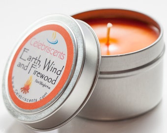 May include: A silver tin candle with an orange candle inside. The label on the tin reads "Celebriscents Earth, Wind and Firewood Net Weight 4 oz. celebriscents.com"