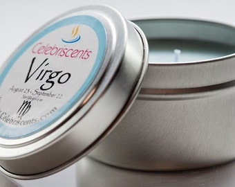 May include: A silver tin candle with a blue label that says "Celebriscents Virgo August 23 - September 22" with a Virgo zodiac symbol. The candle is in a silver tin with a lid.