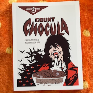 May include: A white box with a red and black illustration of a vampire eating Count Chocula cereal. The box says "Count Chocula" in red and black letters and "Chocolatey Cereal + Marshmallow Bits" in black letters. The vampire has long black hair and is wearing a red shirt. The cereal is in a bowl and there are bats and eyes in the background.