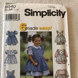 May include: Simplicity sewing pattern number 8540 for girls' dresses. The pattern includes six different styles, including a gingham dress with a ruffled collar and a floral print dress with a ruffled collar. The pattern is for sizes AA 1/2, 1, and 2.