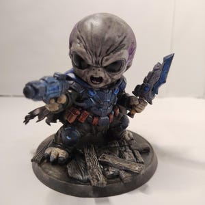 May include: A white ceramic mug with a black handle and the text "But First, Coffee" in a black, handwritten-style font. The mug is on a white surface.