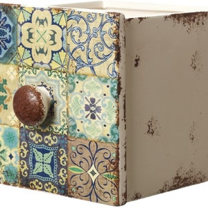 May include: A small, square decorative storage box with a distressed finish. The front features a mosaic of colourful, patterned tiles in shades of blue, green, and yellow. A round, brown knob is centered on the front. The sides are a neutral beige colour.