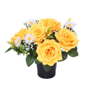 May include: A floral arrangement of yellow roses and white daisies with green leaves, in a black pot. The artificial flowers provide a bright, cheerful aesthetic, suitable for home decor or gifting.