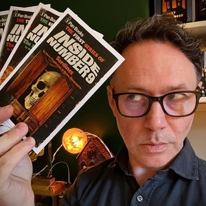 Peut inclure: Une personne tenant une pile de livres broch&eacute;s avec le titre "Inside Number 9: The First Series of Sardines" par Steve Pemberton & Reece Shearsmith.