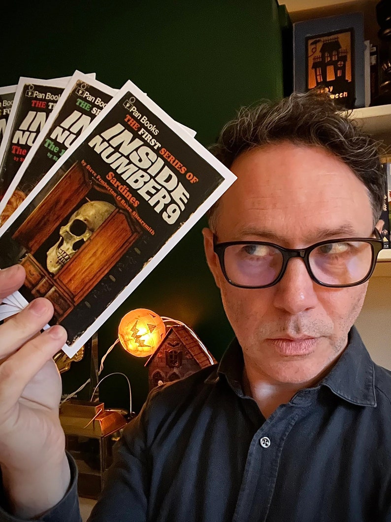 Peut inclure: Une personne tenant une pile de livres broch&eacute;s avec le titre "Inside Number 9: The First Series of Sardines" par Steve Pemberton & Reece Shearsmith.