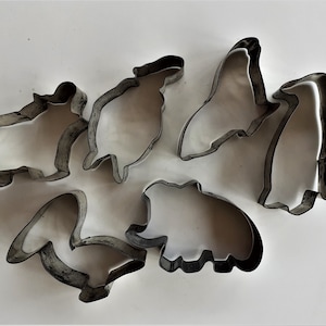 Op de afbeelding: Een set van zes metalen koekjesvormen in de vorm van verschillende dieren. De vormen zijn zilverkleurig en hebben een glanzende afwerking.