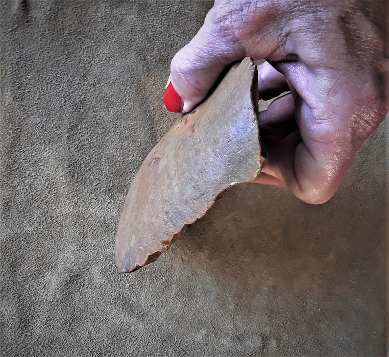 Puede incluir: Una mano sosteniendo una piedra grande, de forma irregular, de color marr&oacute;n con una superficie rugosa y desigual.