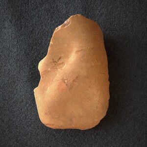 Puede incluir: Una piedra lisa de color marr&oacute;n rojizo con una forma ligeramente irregular. La piedra tiene una textura natural y terrosa.
