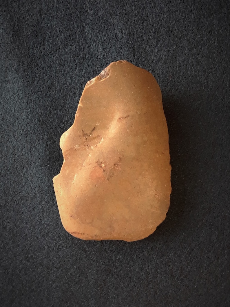 Puede incluir: Una piedra lisa de color marr&oacute;n rojizo con una forma ligeramente irregular. La piedra tiene una textura natural y terrosa.