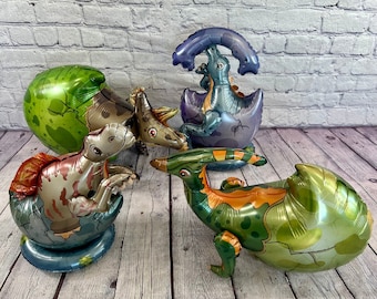 Peut inclure: Quatre jouets de dinosaures gonflables de différentes couleurs, dont le vert, le marron et le bleu. Chaque dinosaure est dans une forme d'œuf éclos, avec le dinosaure qui sort de l'œuf.