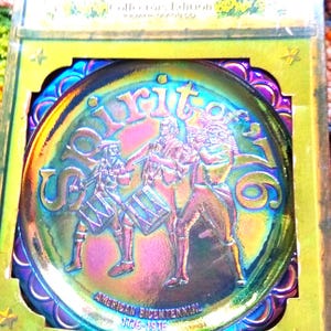 Puede incluir: Plato de vidrio iridiscente con un dise&ntilde;o que conmemora el bicentenario estadounidense. El plato presenta una imagen central de tres figuras tocando tambores, con las palabras "Spirit of 76" y las fechas "1776-1976". El plato est&aacute; en su embalaje original.