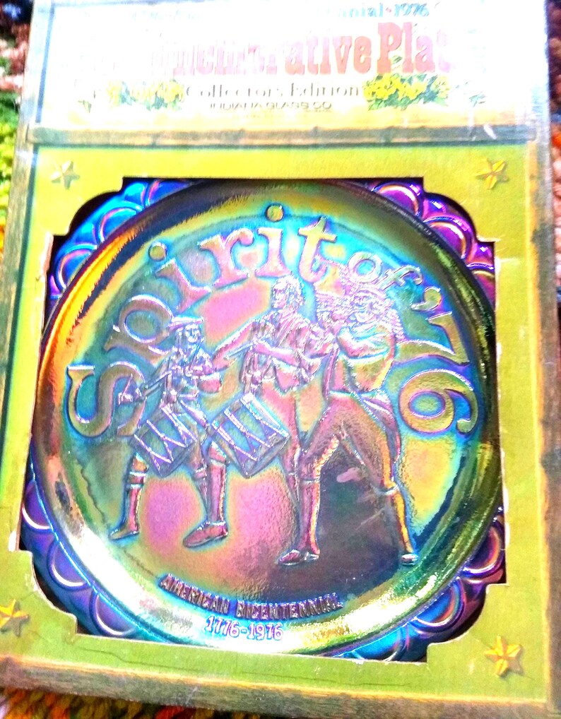 Puede incluir: Plato de vidrio iridiscente con un dise&ntilde;o que conmemora el bicentenario estadounidense. El plato presenta una imagen central de tres figuras tocando tambores, con las palabras "Spirit of 76" y las fechas "1776-1976". El plato est&aacute; en su embalaje original.