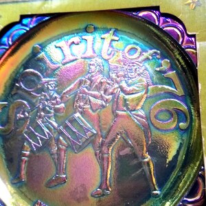 Puede incluir: Plato decorativo iridiscente con tem&aacute;tica patri&oacute;tica. El plato presenta un relieve de tres figuras tocando instrumentos, con las palabras "Spirit of '76" y "American Bicentennial 1776-1976" inscritas.