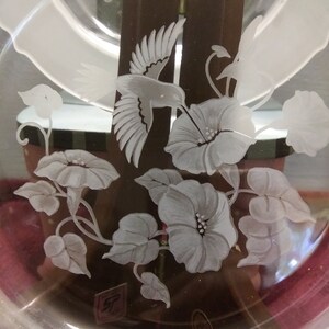 May include: A clear glass plate with an etched design of a hummingbird and flowers. The design is in white and is on a brown background.