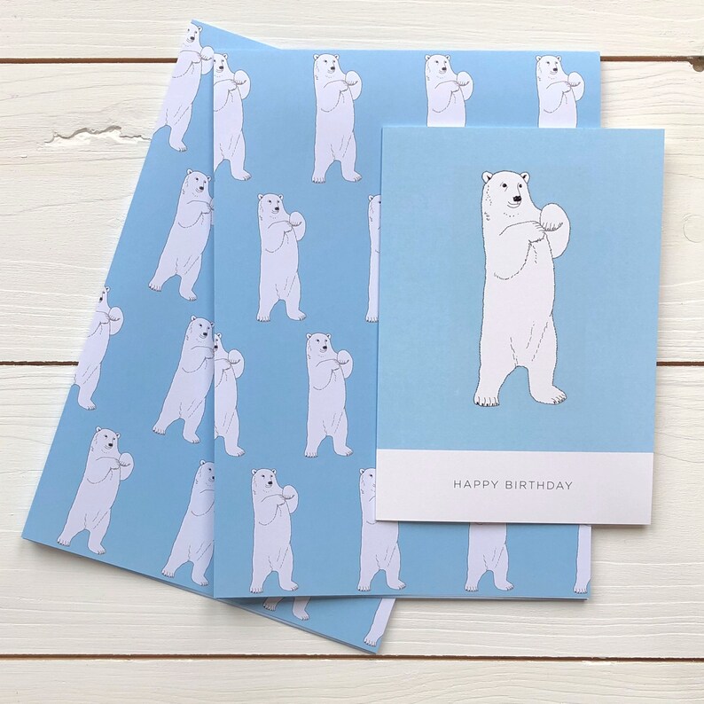 May include: A blue and white birthday card with a polar bear holding a snowball. The card has the text "Happy Birthday" printed on the front.