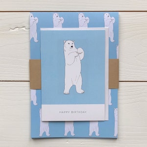 May include: A blue and white birthday card with a polar bear illustration and the text "Happy Birthday". The card is wrapped in blue wrapping paper with a repeating pattern of polar bears.