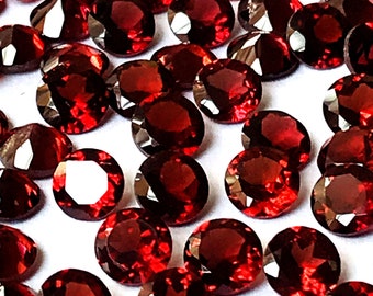 May include: A collection of round, red gemstones. The gemstones are smooth and shiny, with a deep red color.