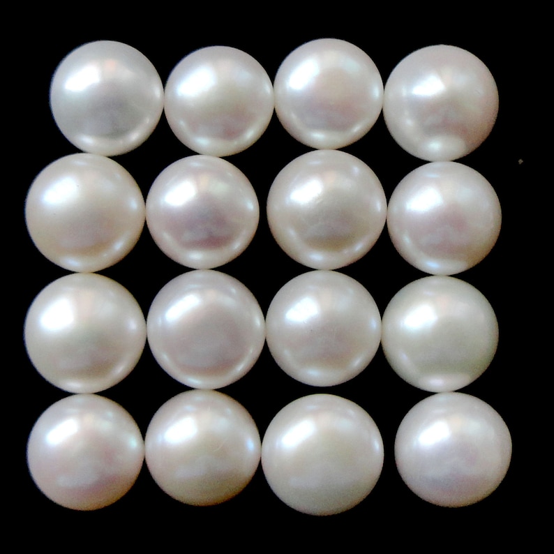 May include: A collection of 16 white round pearls arranged in a grid pattern.