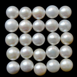 May include: A collection of 25 white round pearls arranged in a grid pattern on a black background.