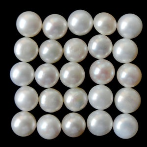 May include: A collection of 25 white round pearls arranged in a grid pattern on a black background.