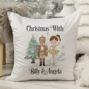 May include: White cushion with a Christmas-themed design featuring a nutcracker and a ballerina. The text "Christmas With Billy & Angela" is printed on the cushion.