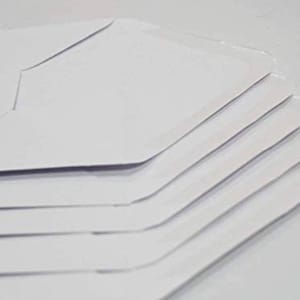 Puede incluir: Una pila de sobres blancos, doblados y listos para usar para enviar cartas o documentos.
