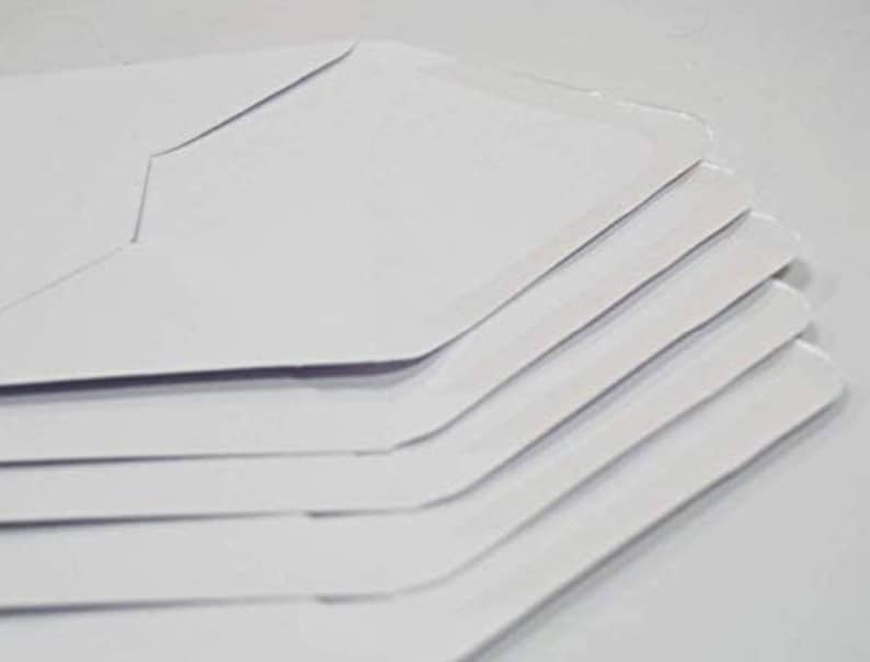 Puede incluir: Una pila de sobres blancos, doblados y listos para usar para enviar cartas o documentos.