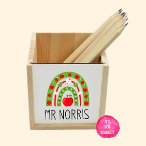 May include: Wooden pencil holder with a rainbow design featuring red apples and the text "MR NORRIS".