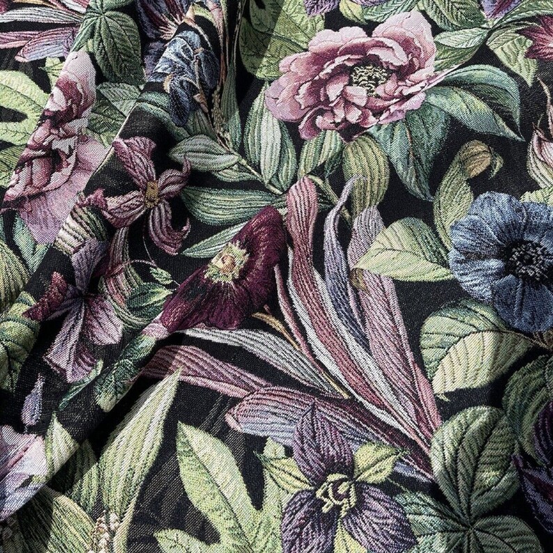 May include: A black fabric with a floral pattern featuring pink, purple, and blue flowers. The fabric has a textured, woven look.