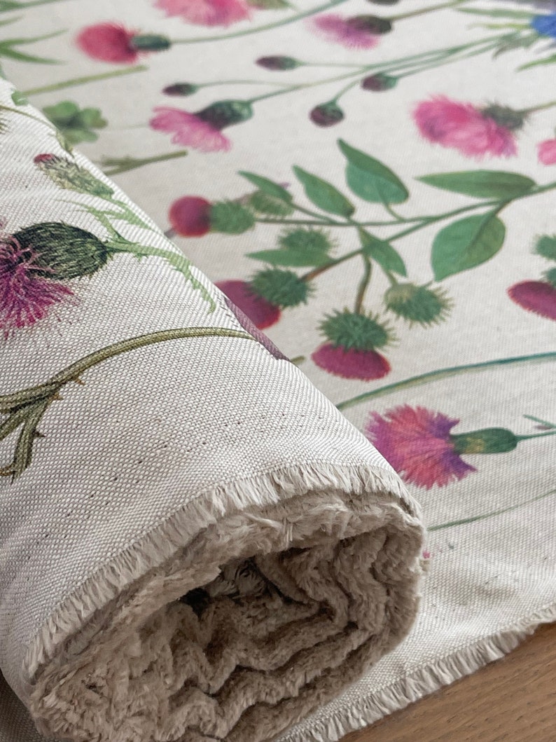 Wildflower linen-look fabric roll featuring pink thistles and green foliage, ideal for curtains, blinds, or soft furnishings – detailed view