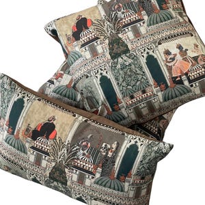 Puede incluir: Tres almohadas decorativas con un dise&ntilde;o estampado en verde, marr&oacute;n y beige que presenta una ilustraci&oacute;n intrincada de personas y edificios. El patr&oacute;n recuerda al arte tradicional indio.