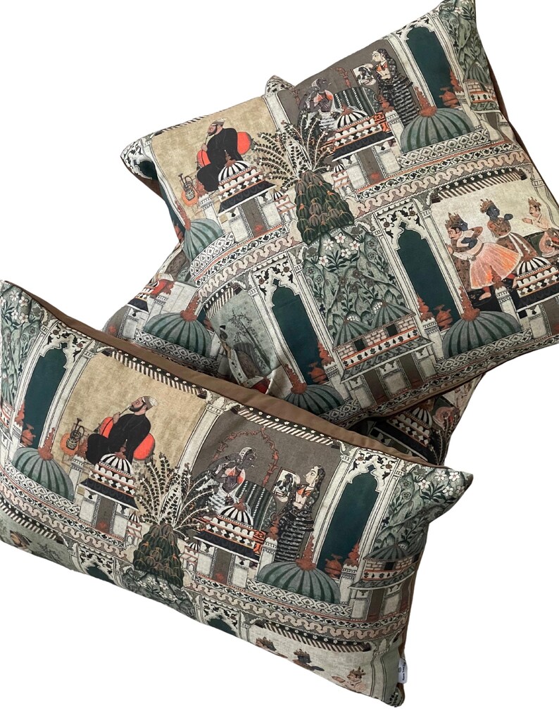 Puede incluir: Tres almohadas decorativas con un dise&ntilde;o estampado en verde, marr&oacute;n y beige que presenta una ilustraci&oacute;n intrincada de personas y edificios. El patr&oacute;n recuerda al arte tradicional indio.