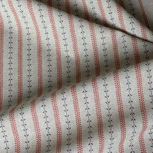 Softly folded yardage highlights the natural woven texture and small-scale botanical pattern.