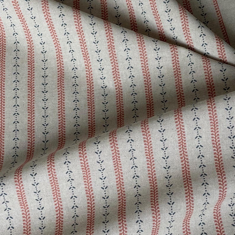 Softly folded yardage highlights the natural woven texture and small-scale botanical pattern.