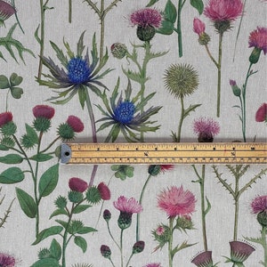 Natural linen-look fabric with Scottish thistle and wildflower print, shown with tape measure to display pattern scale for curtains and crafts