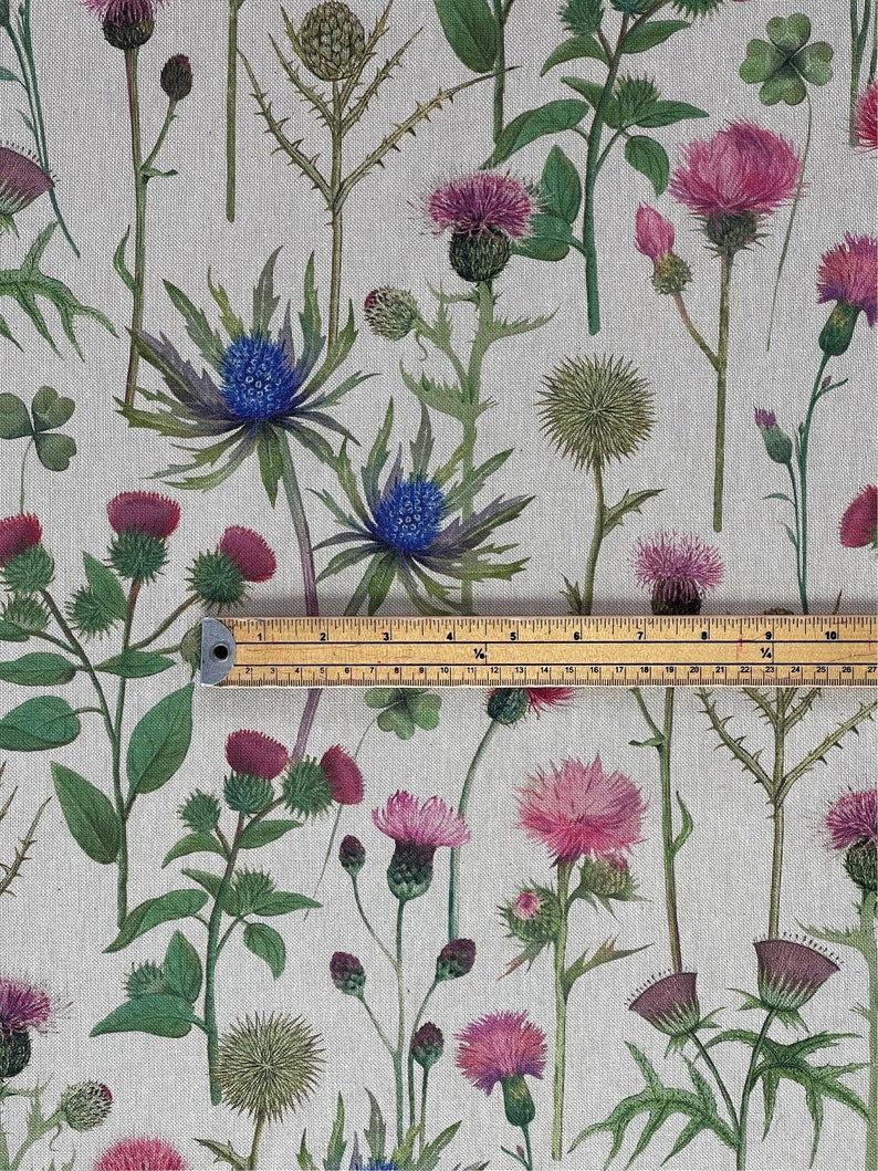 Natural linen-look fabric with Scottish thistle and wildflower print, shown with tape measure to display pattern scale for curtains and crafts