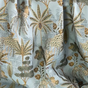 May include: A blue fabric with a repeating pattern of green and gold palm trees, flowers, and leaves.