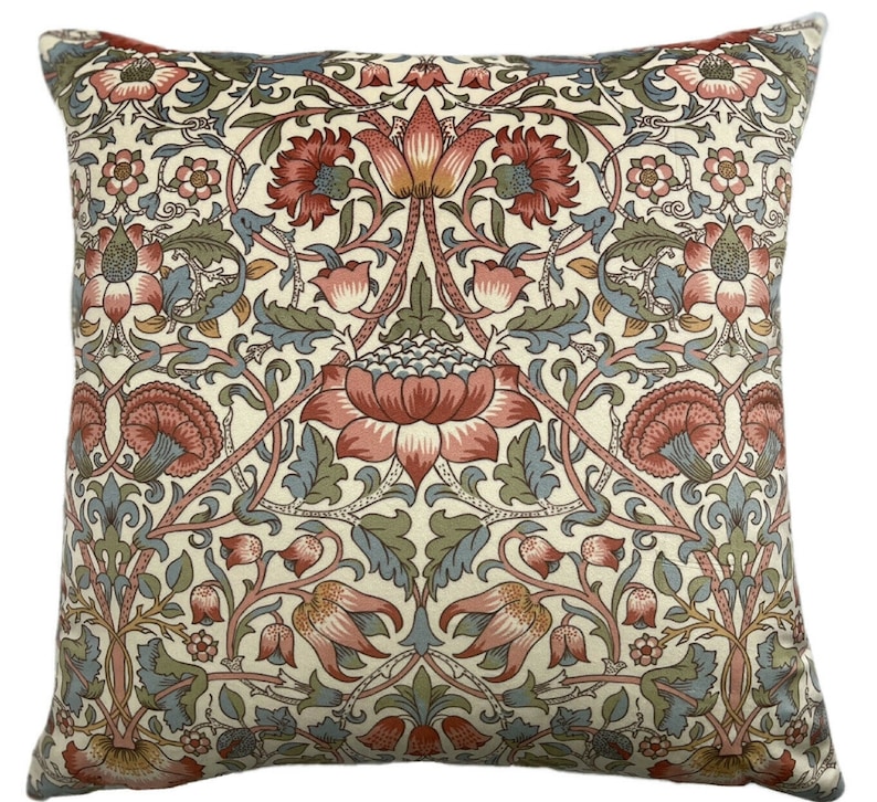 May include: A cream-colored throw pillow with a floral pattern in shades of red, blue, and green. The pattern features stylized flowers and leaves.