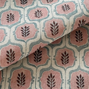 Puede incluir: Primer plano de una tela con un patrón repetitivo. El diseño presenta motivos florales rosas, azules y marrones sobre un fondo color crema. La tela está doblada, mostrando la textura y la profundidad del material. Ideal para tapicería o decoración del hogar.