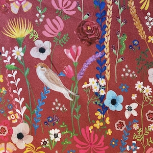 May include: A red fabric with a floral pattern featuring a variety of flowers, leaves, and a small bird. The flowers are in shades of pink, purple, blue, and yellow. The bird is brown and white.
