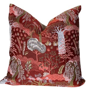 May include: Red velvet pillow with a gold and white embroidered floral pattern featuring trees, leaves, and flowers.