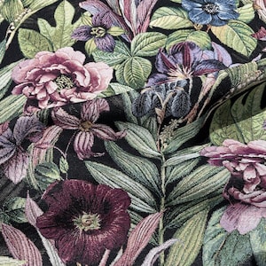 May include: A black fabric with a floral pattern featuring pink, purple, and green flowers. The fabric has a textured, woven look.