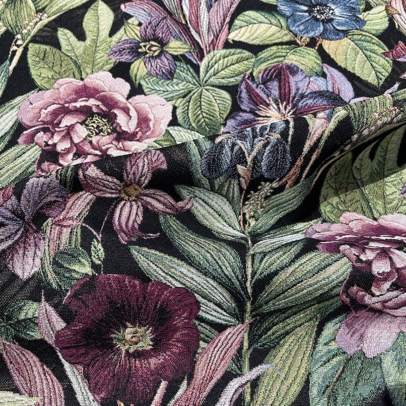 May include: A black fabric with a floral pattern featuring pink, purple, and green flowers. The fabric has a textured, woven look.