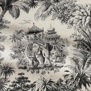 May include: Black and white toile fabric depicting an elephant with passengers under a canopy, set within a tropical landscape with detailed architecture. The design creates a sense of travel and adventure.