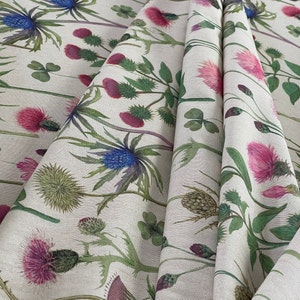 Floral wildflower fabric in soft pink, blue, and green tones on beige linen-look cotton – close-up of folded material ideal for curtains or cushions.