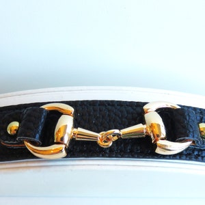 May include: Black leather bracelet with a gold-tone horse bit buckle.