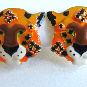 May include: A pair of orange, brown, black, and white enamel tiger head earrings with red rhinestone accents.