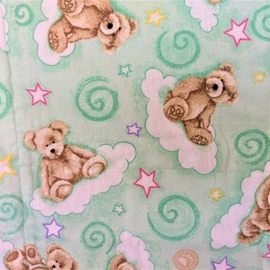 May include: A green fabric with a repeating pattern of brown teddy bears sitting on white clouds, green swirls, and pink, purple, and yellow stars.